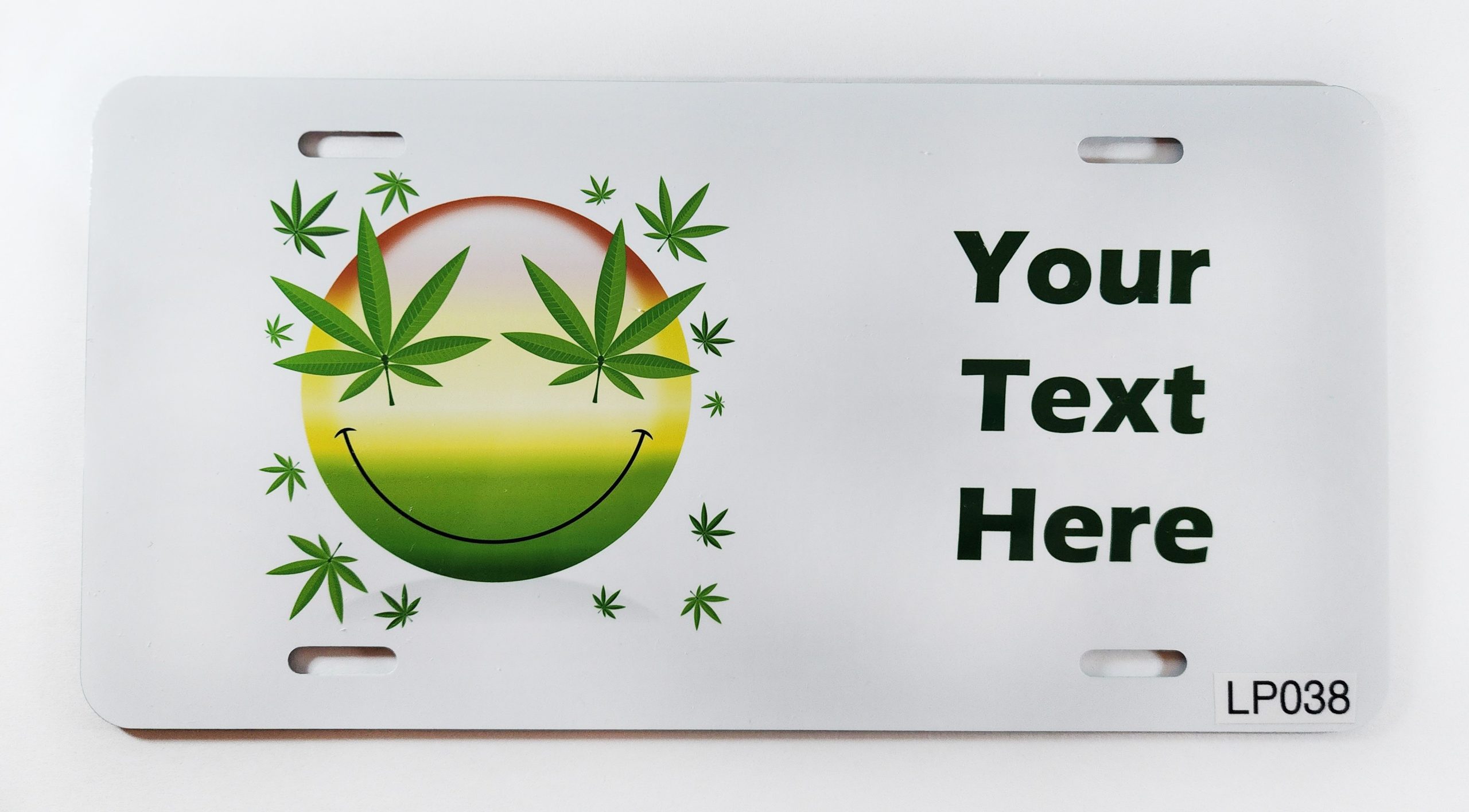 A white license plate with a marijuana leaf smiley face.