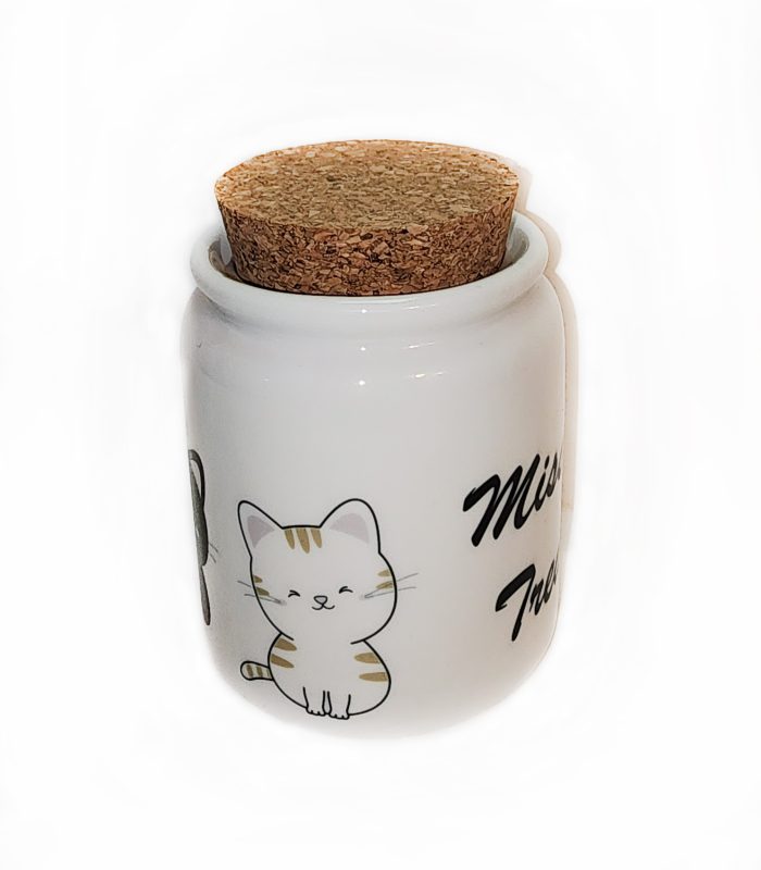 A white jar with a cork lid sitting on top of it.