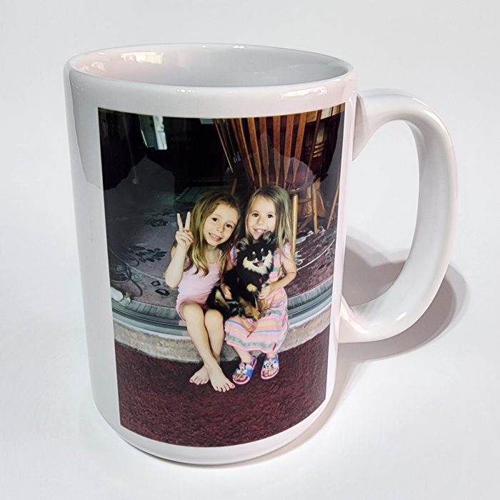 A white coffee mug with two girls and a cat.